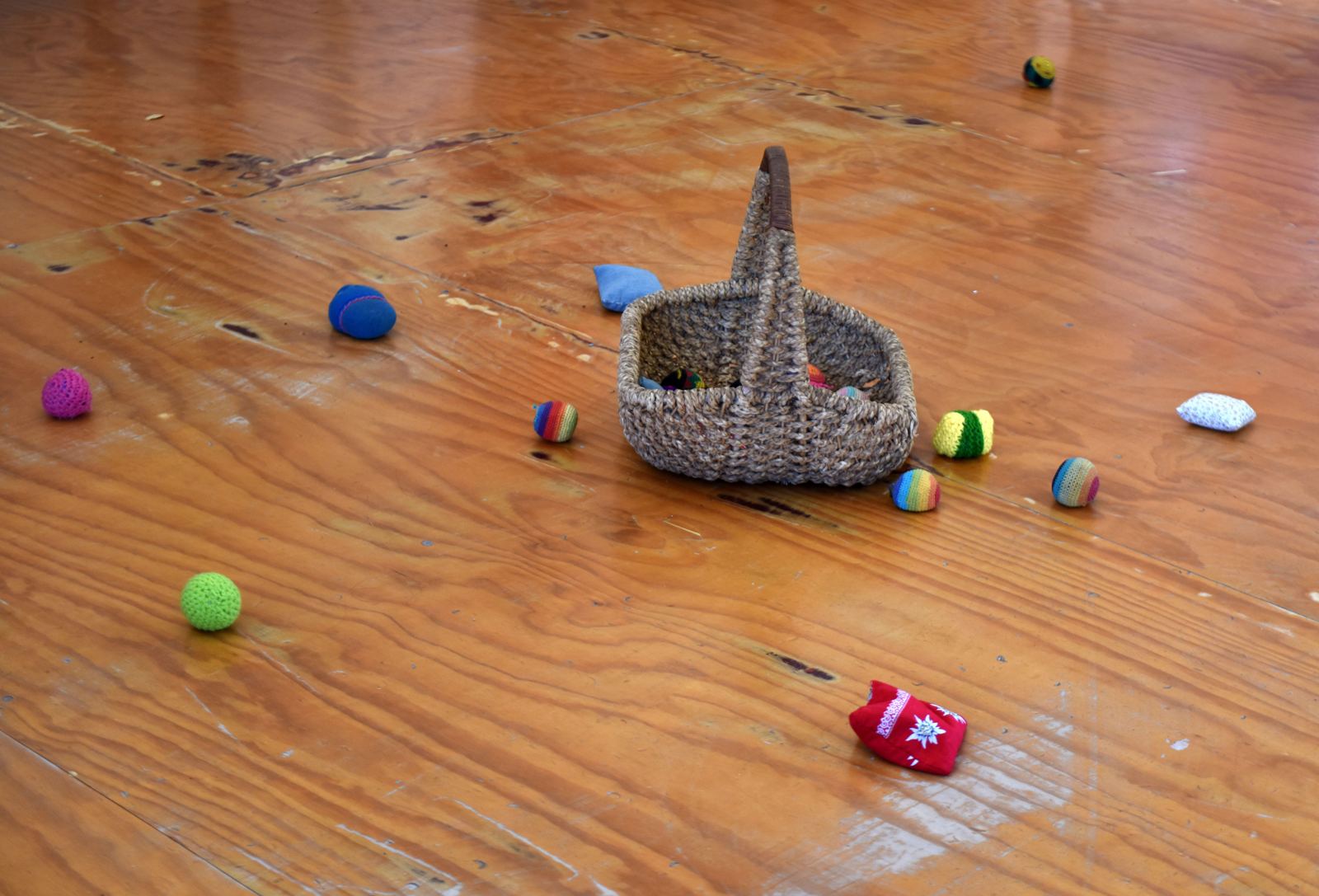 Cesta de mimbre y pelotas de colores sobre el piso de madera