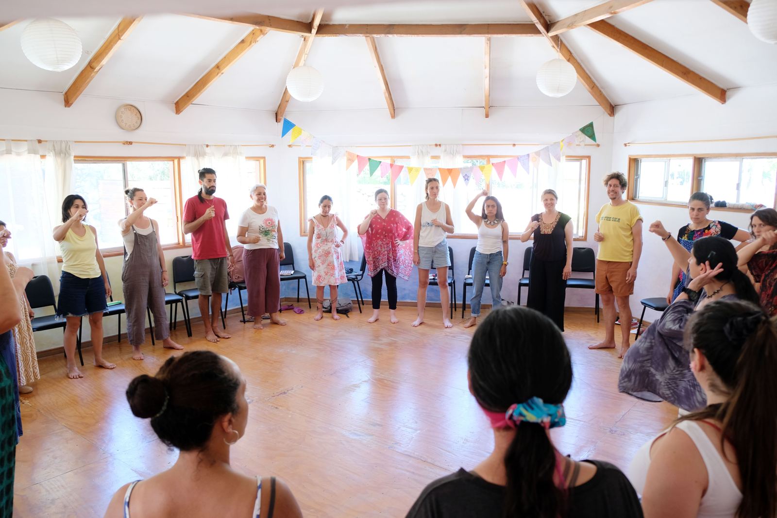Participantes de pie formando un círculo en la sala del seminario